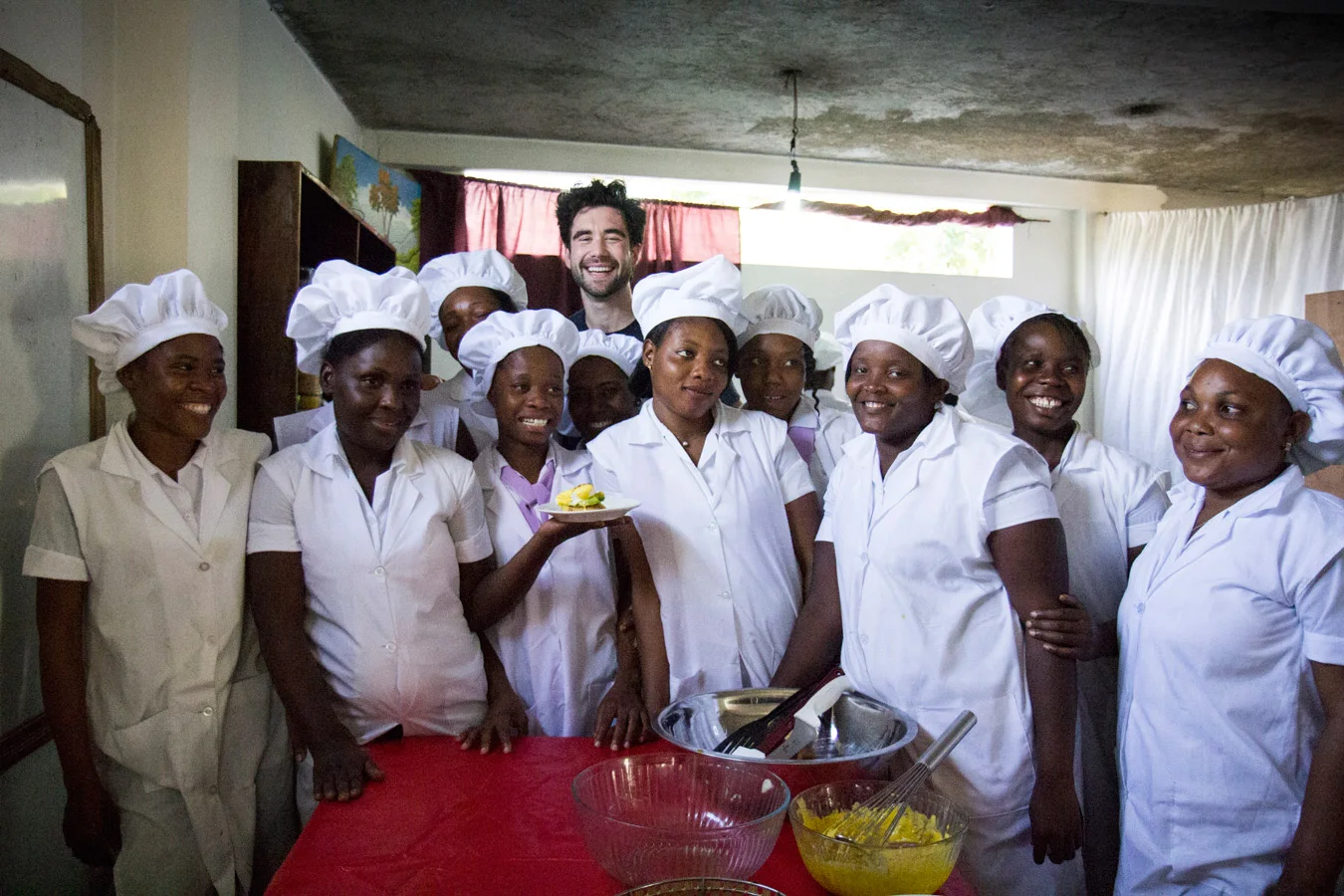 A chef and his students smiling in a group photo.
