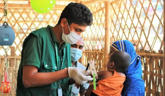 Man in medical mask assesses child