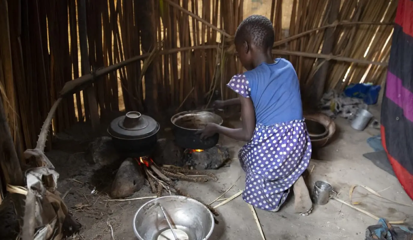 A young girl tends a cooking fire in South Sudan A young girl tends a cooking fire in South Sudan