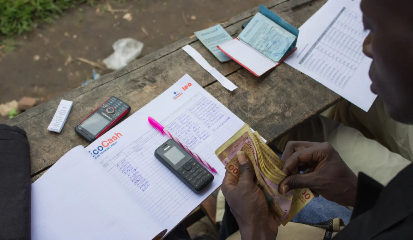 Man counts money he is handing out over a ledger book.