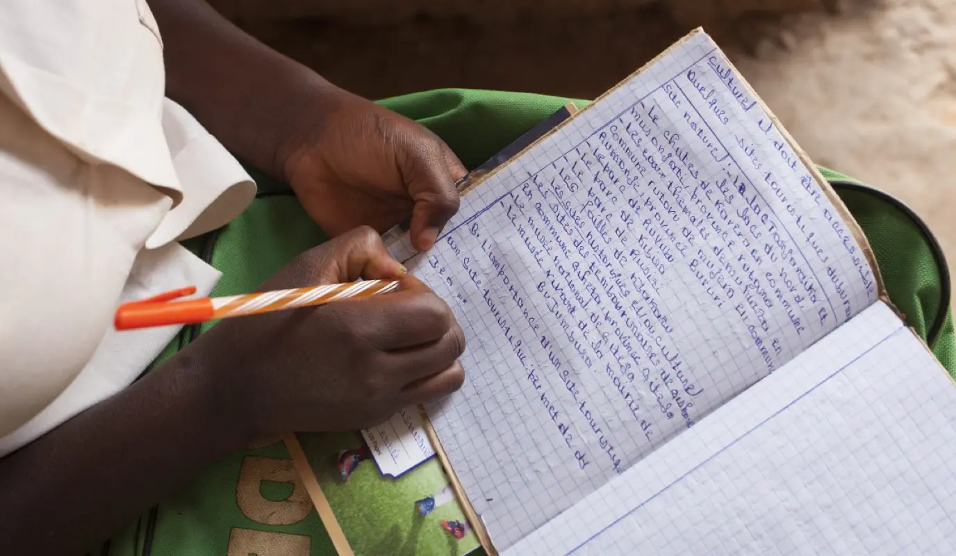 Amida Tuyishimire (14), daughter of Violette Bukeyeneza with her school books and pens for the education she is now able to receive because of the Graduation Program at her home in Bukinanyana, Cibitoke, Burundi