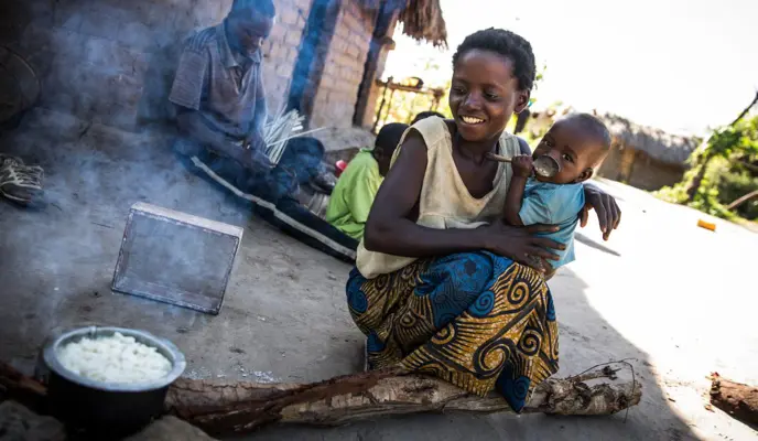 A mother prepares breakfast to share with her husband, their children, and cousin in the village of Pension, Manono Territory, DRC.