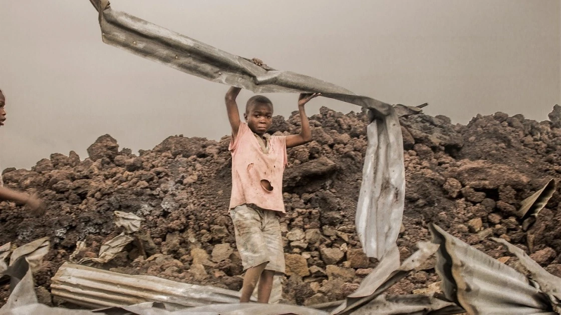 Amani from the Buhene district in the north of Goma, collects the rubble after a volcanic eruption. (Photo Esdras Tsongo/Concern Worldwide)