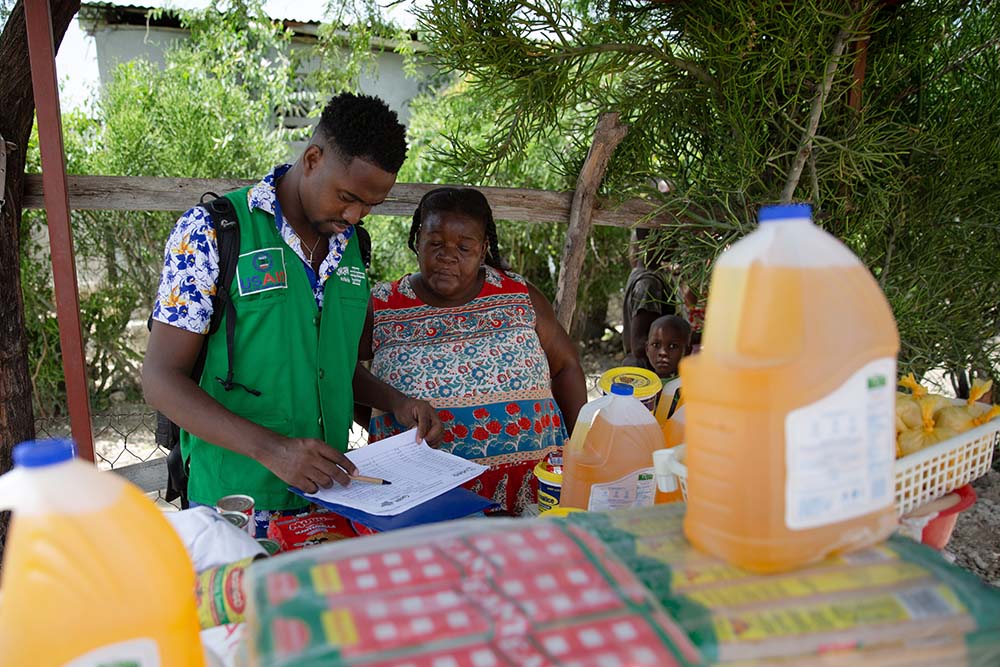 Concern's Sadrac Antoine with Justa Ernice, a small trader in the Cité Soleil area of Port-au-Prince, Haiti who has worked with Concern to develop her business. She is now a registered vendor for the USAID-funded Manje Pi Byan program. (Photo: Kieran McConville/Concern Worldwide)