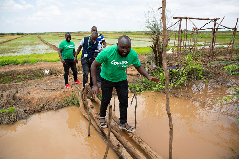 concern staff crossing a makeshift bridge in Kenya