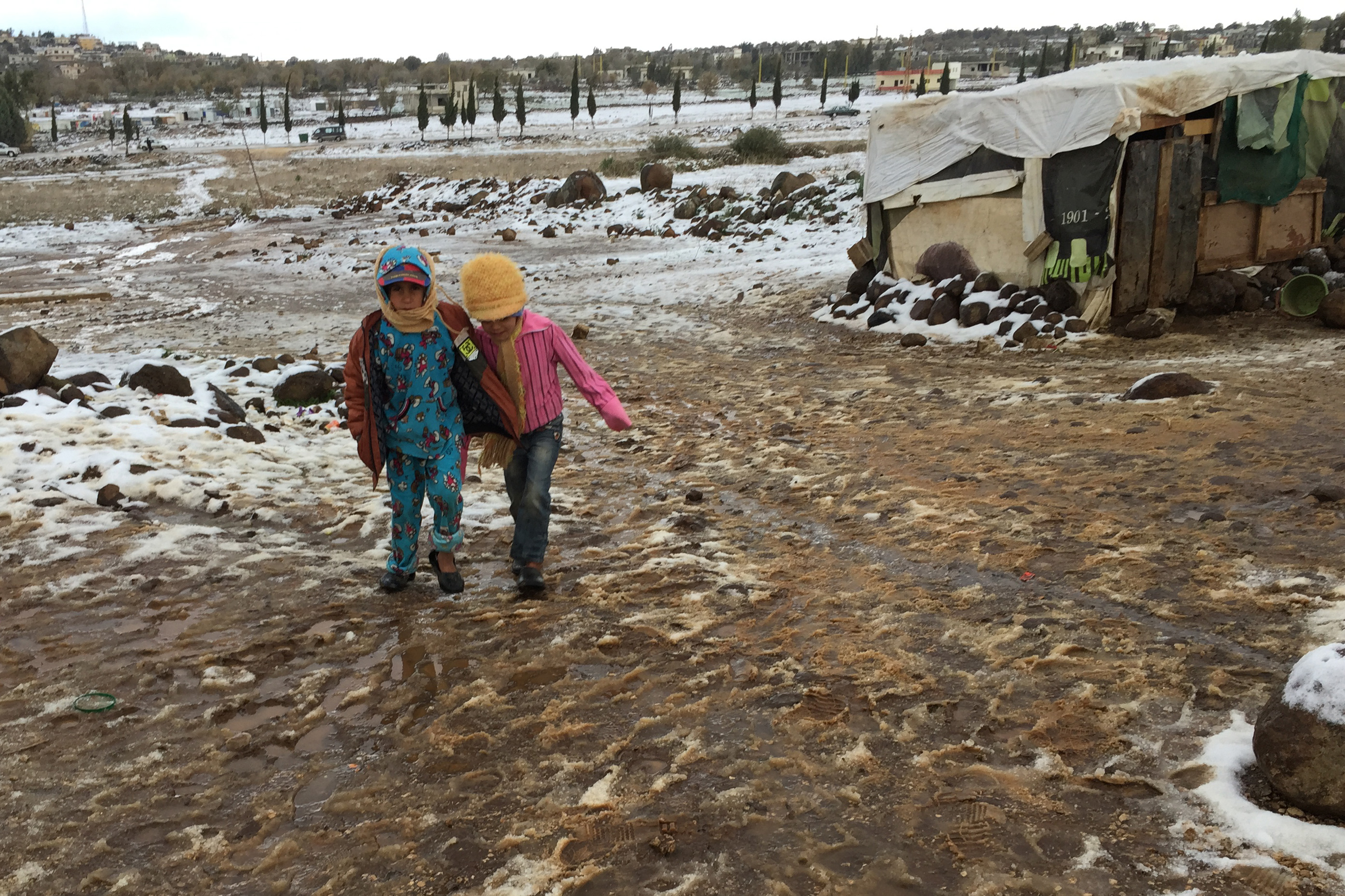 Syrian refugee children try to make their way through the snow and slurry in Lebanon.