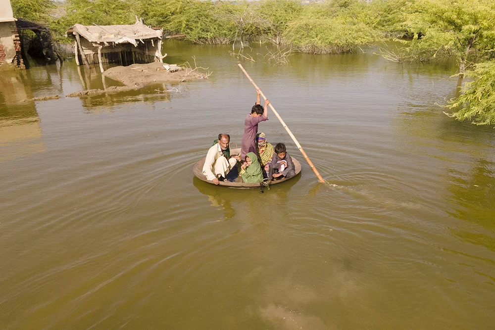 Aqib Aliin transports people on a frying pan across the flooded waters in Sindh, 2022. (Photo: Emmanuel Guddo/Concern Worldwide)