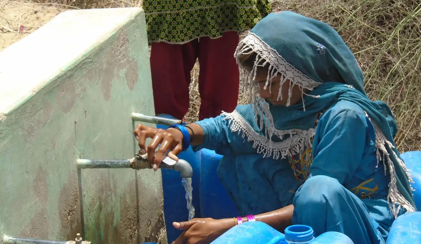 Young woman getting water from a well in Pakistan