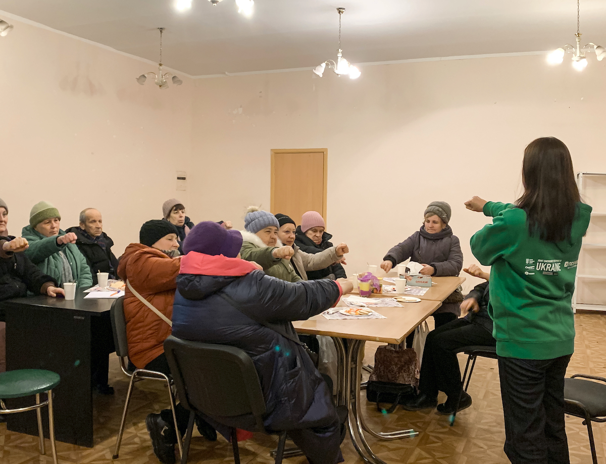 Olek* and Veronika* (in the back, left) participate in a psychosocial support group session led by Lilia (right, in the green sweatshirt). Lilia's group meets weekly to help older Ukrainians cope with the traumas brought on by the war.