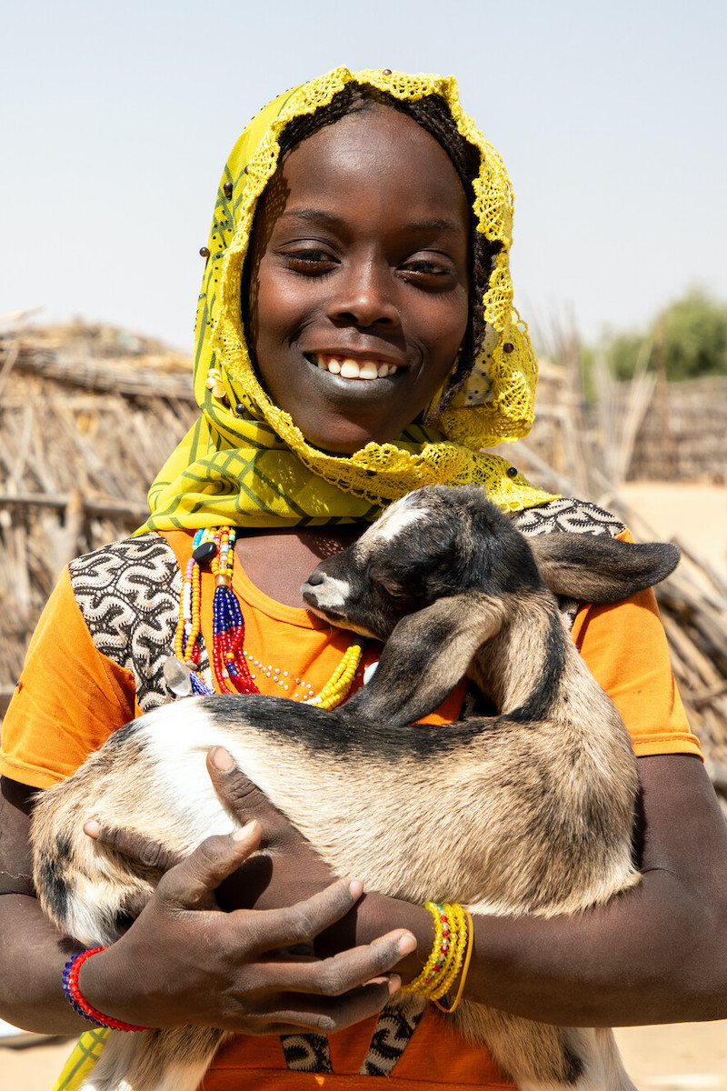 Mariam Adam holds up one of her family's goats in Lac Province, Chad