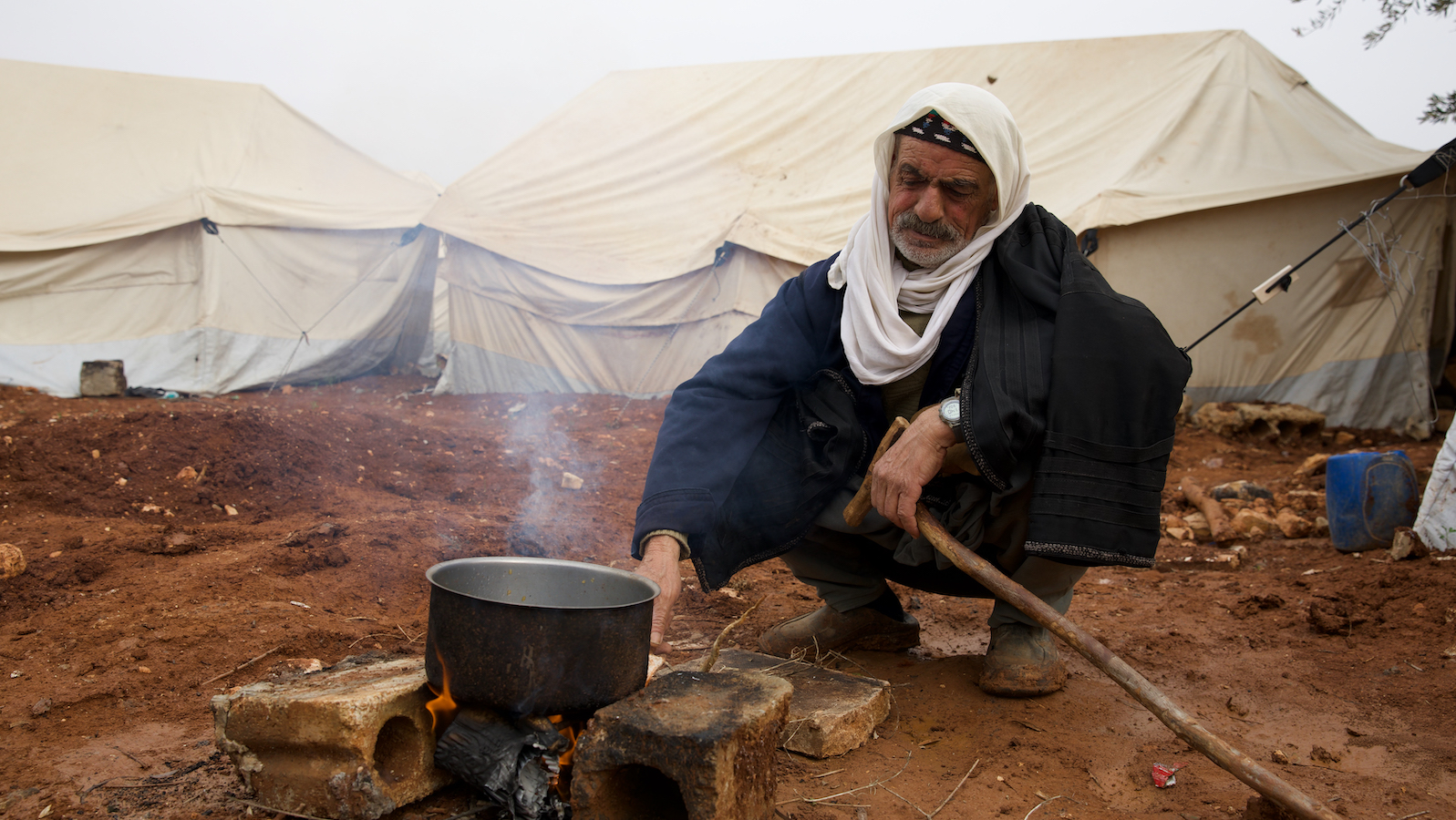 Omar* (66) is forced to make a fire to cook his food. He uses cardboard, dry sticks, and nylon bags to start the fire, which he makes sure it is far from his tent. (Photo: Ali Haj Suleiman/DEC/Fairpicture)