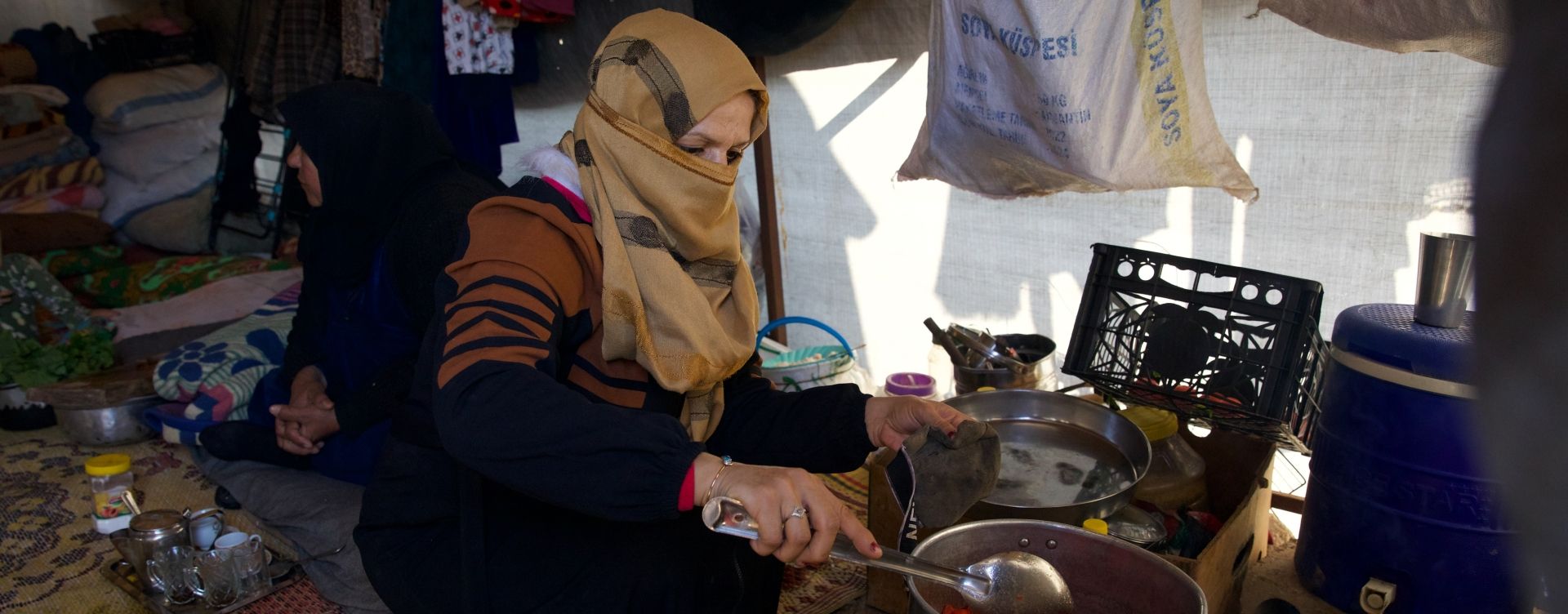 Reem* (30) prepares food for her husband Jaafar* (32) and her children inside their tent in the Ahl al-Khair camp, Syria. (Photo: Ali Haj Suleiman/DEC/Fairpicture)