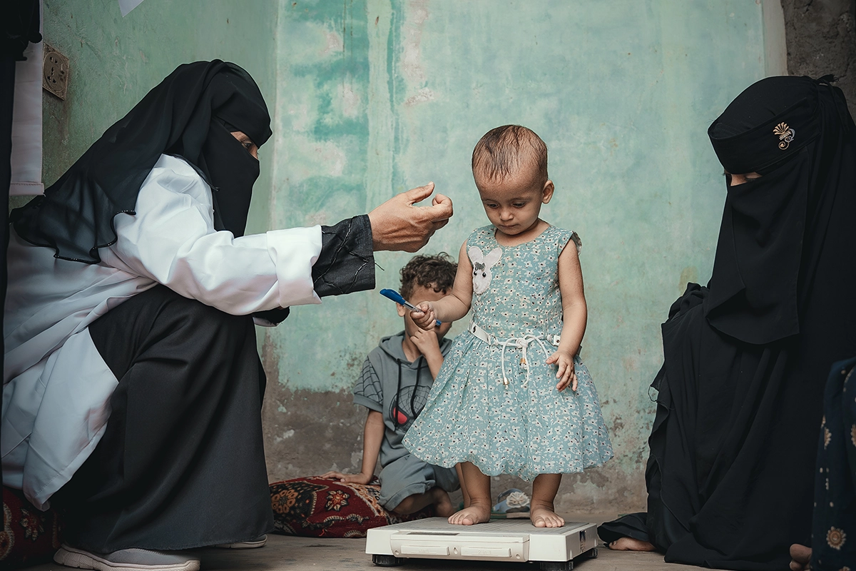 Rima* with her mother and Nabilah Mohammed, the Community Health Volunteer (CHV). Rima received treatment for malnutrition in a health center supported by Concern in Al-Shaqa’a village, Tuban district.
