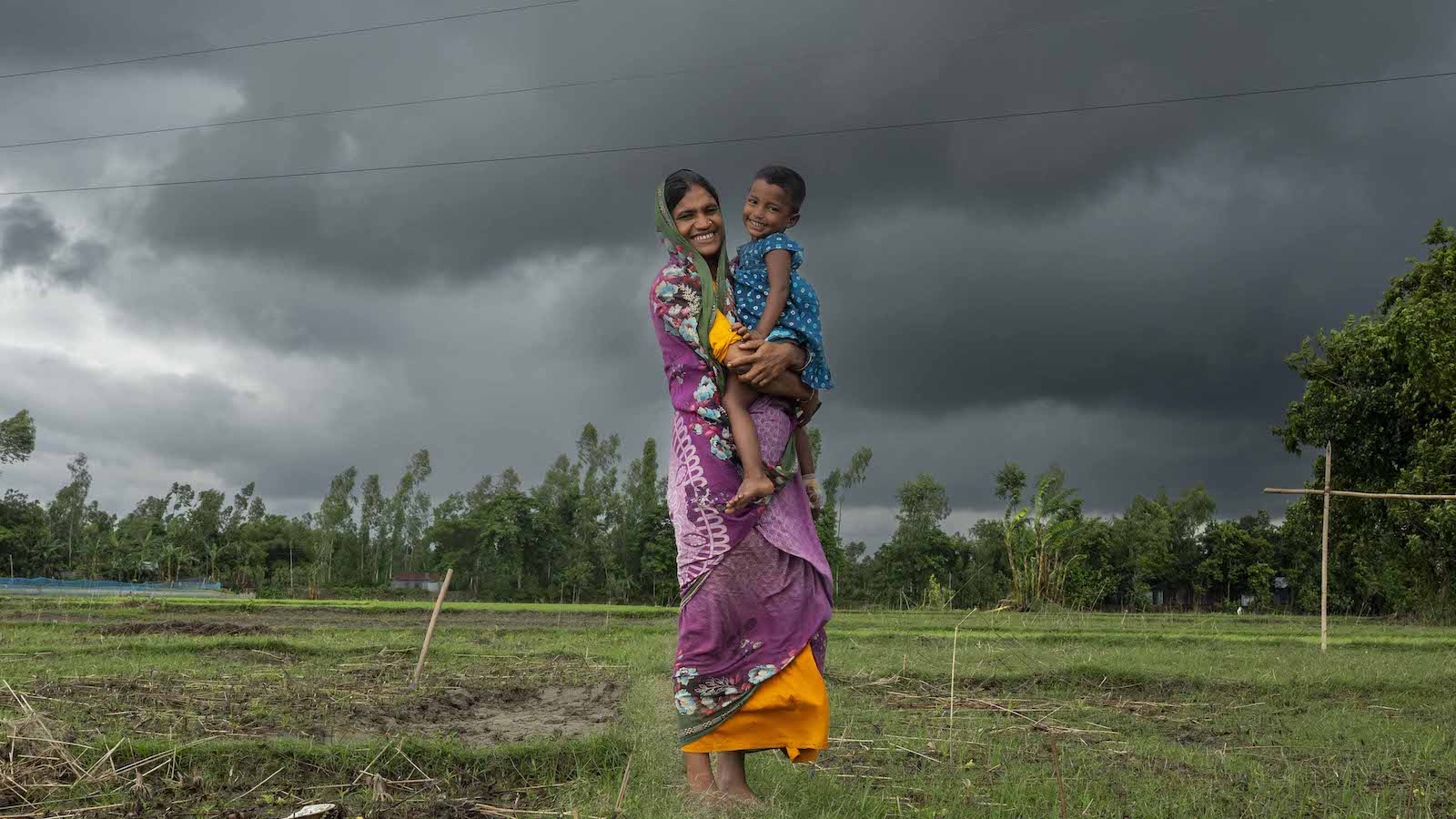 Mst. Sumi Begum (26), holds her daughter Hia Moni (3). Once displaced by flooding, Sumi's family has now returned here to their native village in Charitabari in Sundarganj, thanks to the flood-resistant housing implemented by Gana Unnayan Kendra, with the support of Concern Worldwide. Photo: Saikat Mojumder/Concern Worldwide