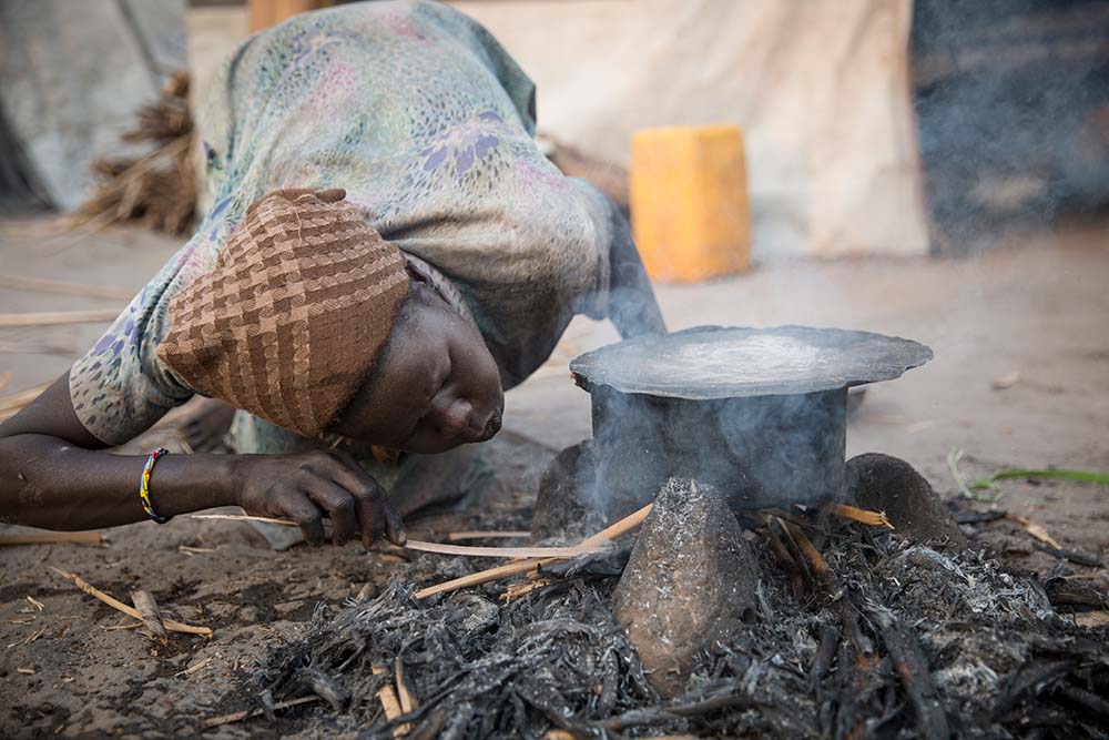 A woman starts a cooking fire at the temporary settlement built on Kok Island in the swamps of Unity State. During the South Sudanese Civil War, people began hiding on the islands from fighting. (Photo: Kieran McConville/Concern Worldwide)