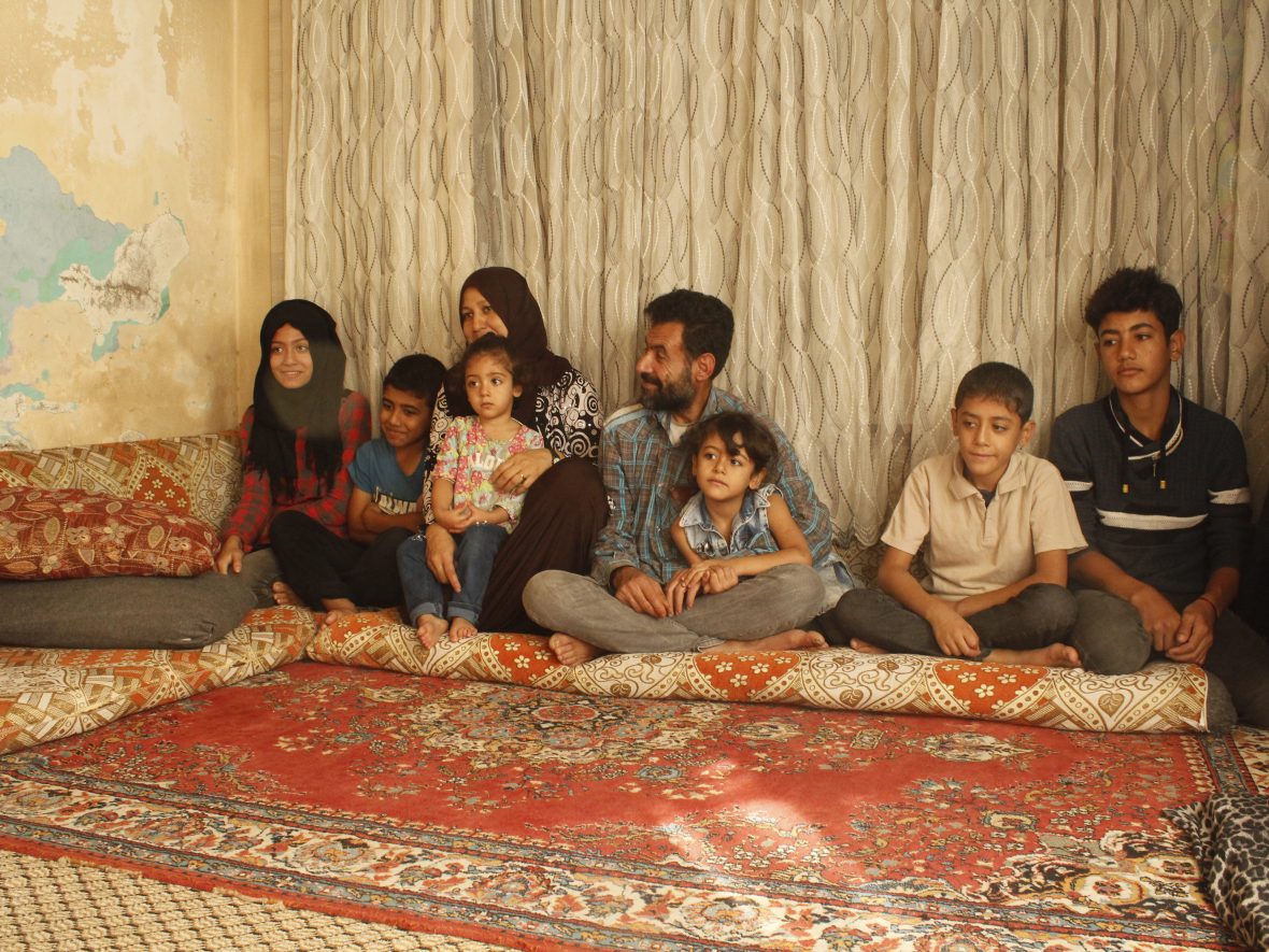 A family sitting on a rug.