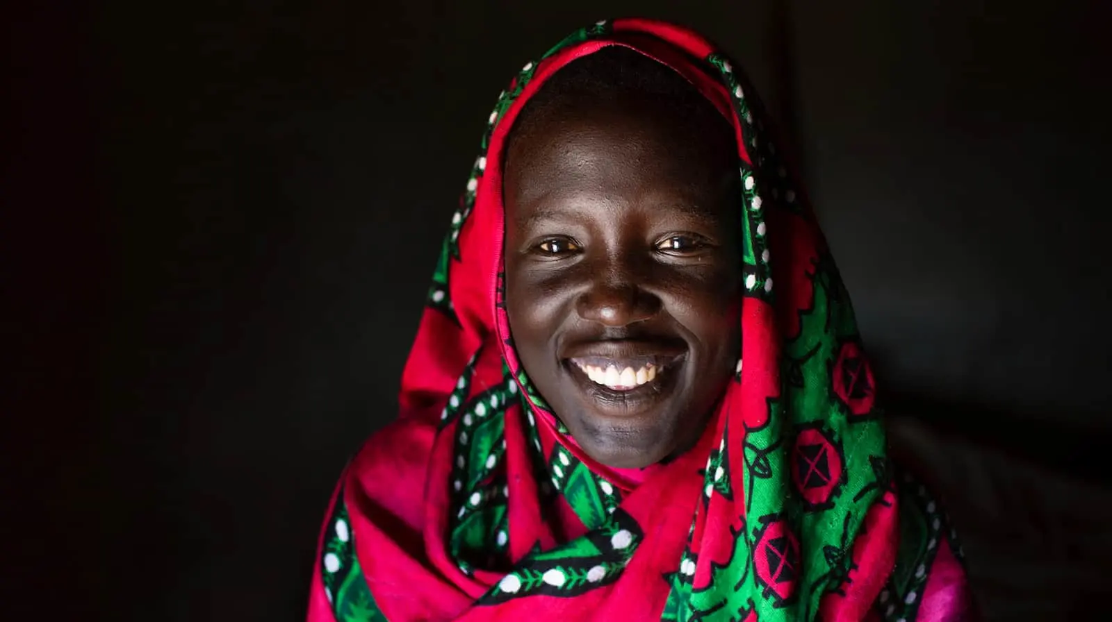 Woman smiling at the camera wearing a colorful garment.