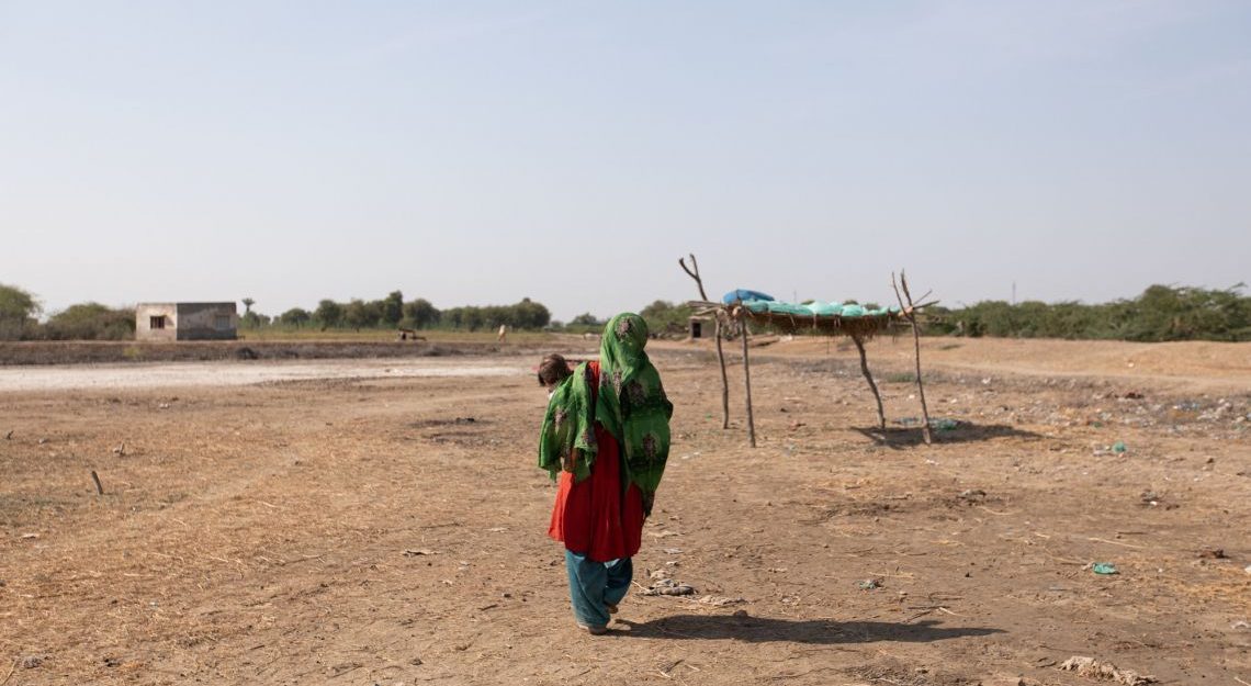A woman and child walking across a dry landscape.