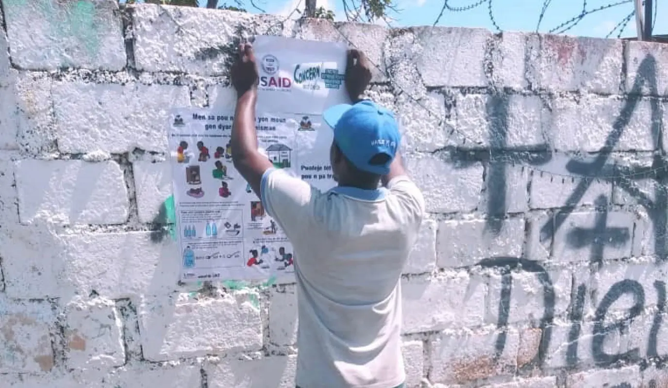 In Cité Soleil, Agents de Santé hang information posters as part of a response to the recent cholera outbreak.