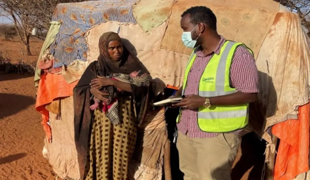 A young Somali mother standing next to a man from Irish charity Concern Worldwide.