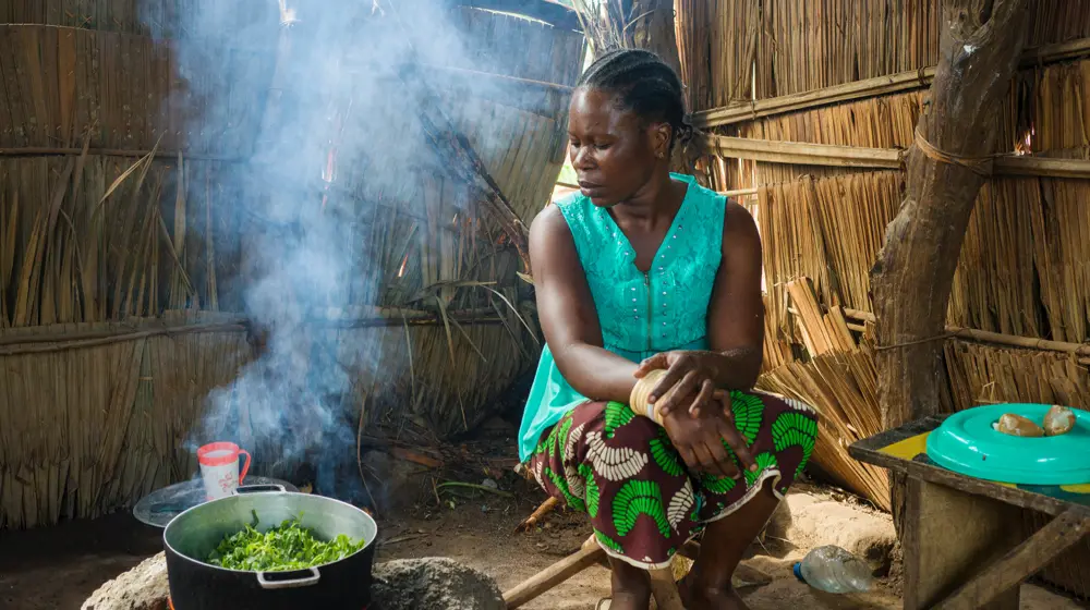 Central African mother-of-four Hermine Kounougoue (27) prepares a meal of amaranth leaves, peanut paste, and plantain after a cooking demonstration with her neighbor Nadine Doko, a Concern-supported Mama Lumiere – or “lead mother.” Hermine and her family have benefitted from Nadine’s help. (Photo: Chris de Bode)