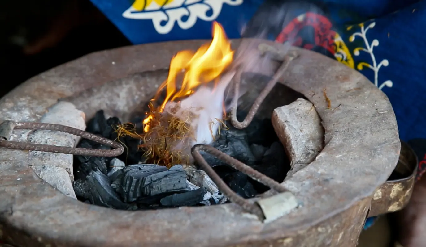 Closeup of the top of a hand made eco stove, with flaming charcoal